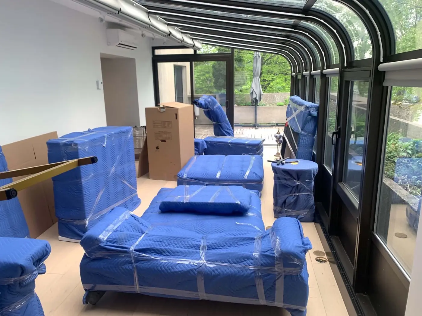 Furniture wrapped in blue blankets in a sunroom